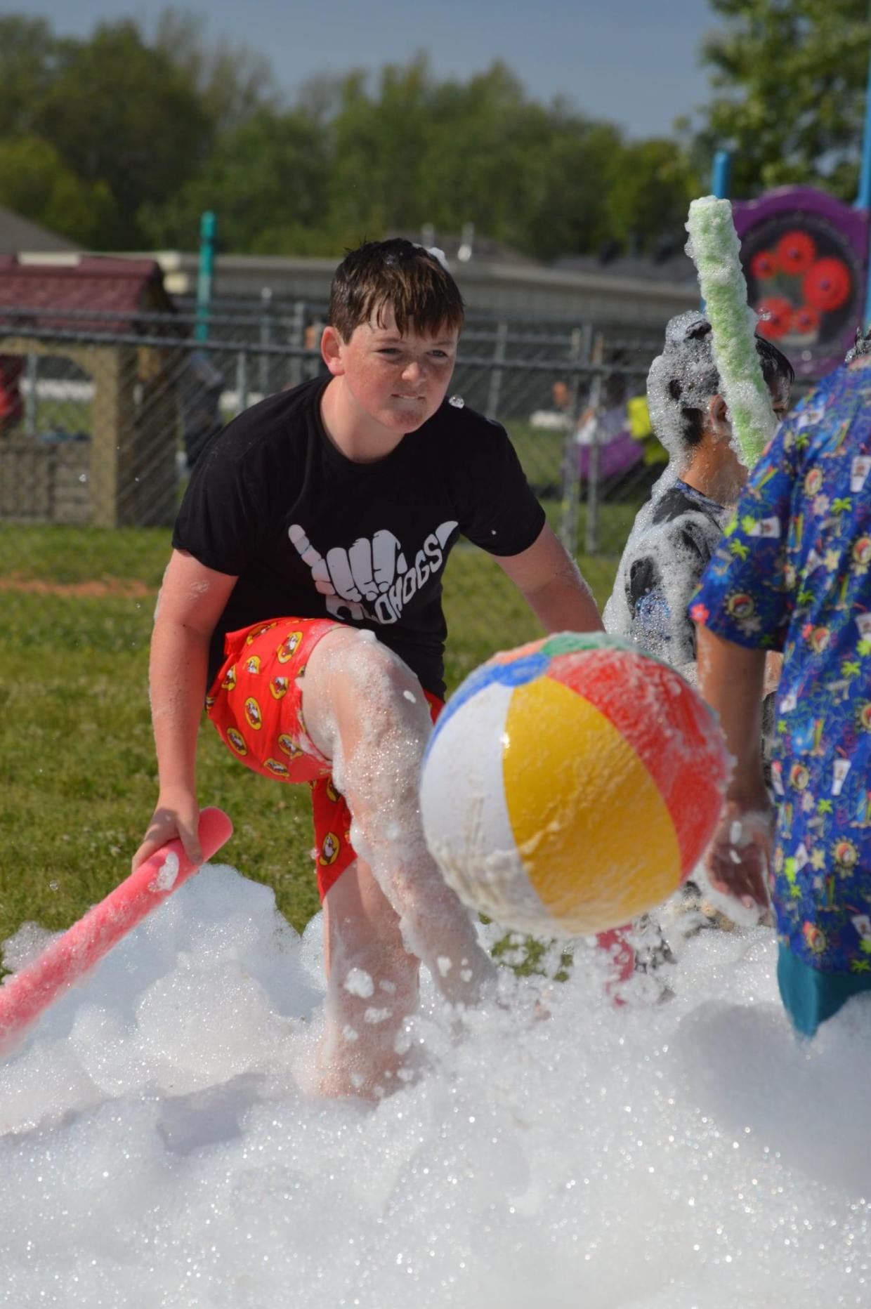 Elementary students running through non‑toxic foam at a Northwest Arkansas school field day